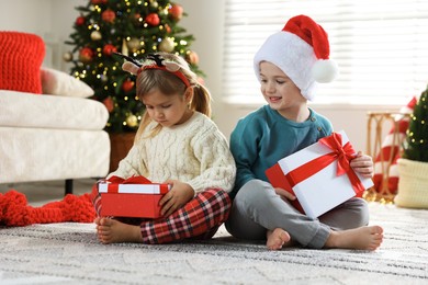 Photo of Happy children with Christmas gifts on floor at home