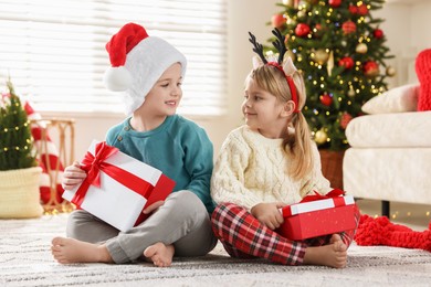 Photo of Happy children with Christmas gifts on floor at home