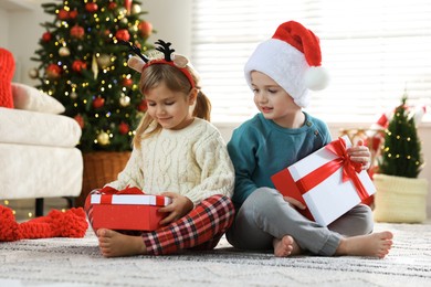 Photo of Happy children with Christmas gifts on floor at home