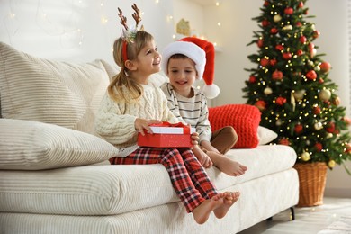 Photo of Happy children with Christmas gift on sofa at home