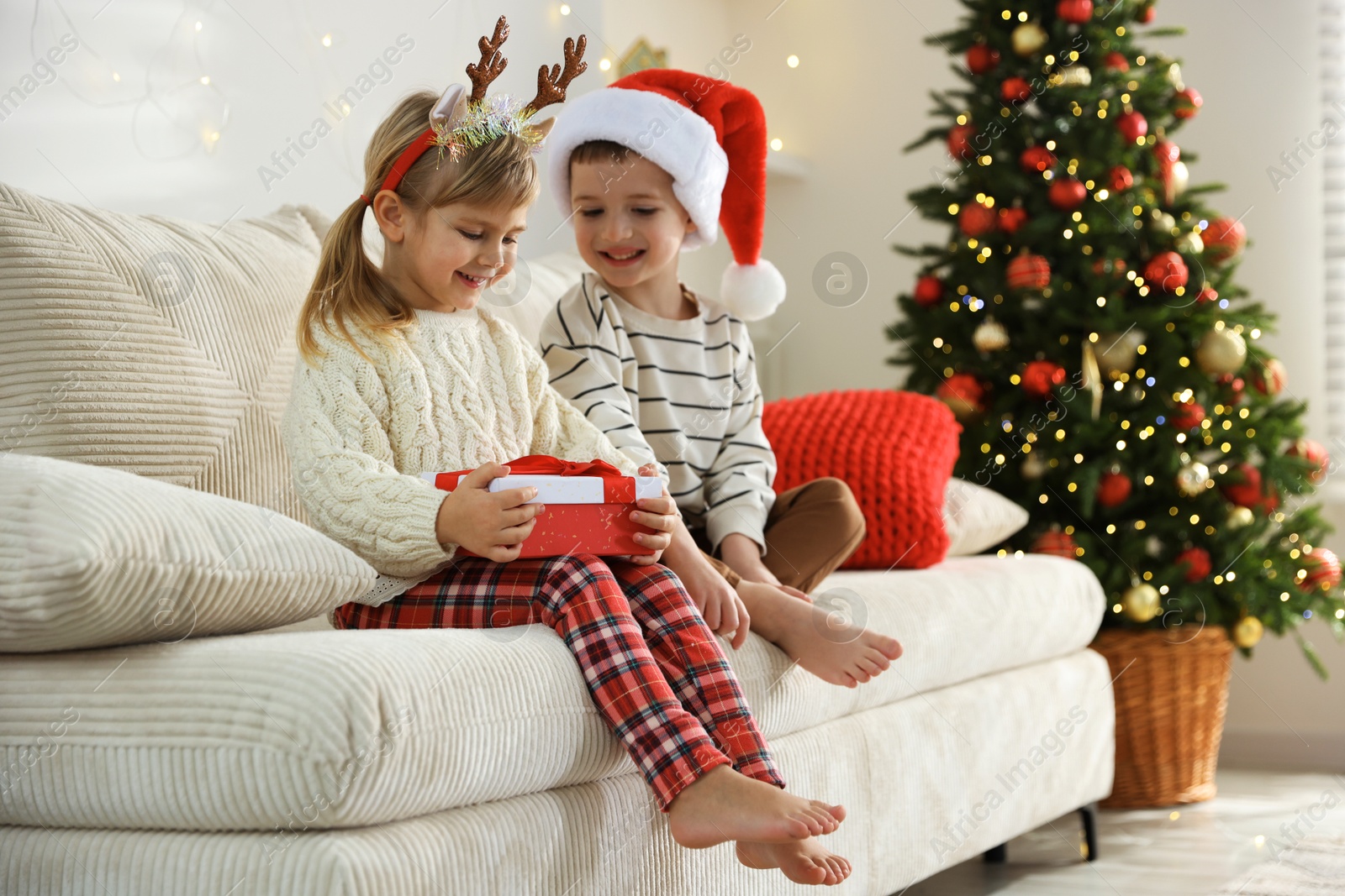 Photo of Happy children with Christmas gift on sofa at home