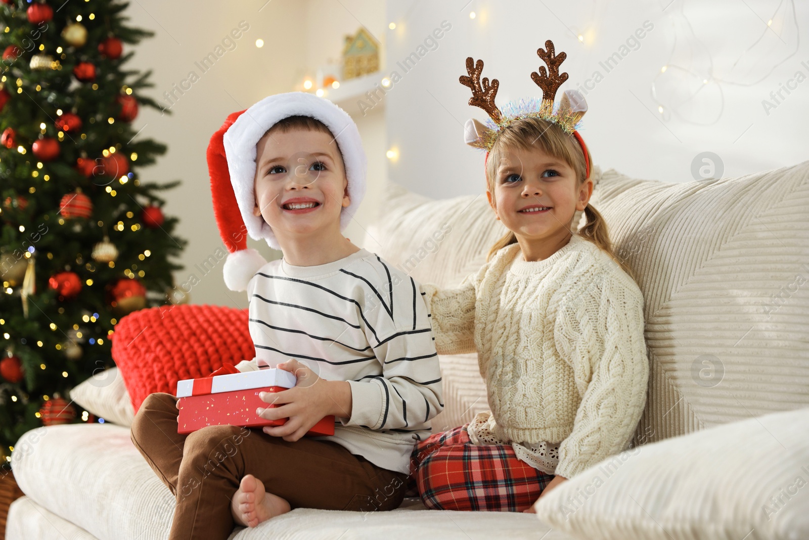 Photo of Happy children with Christmas gift on sofa at home