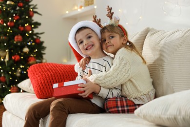 Photo of Happy children with Christmas gift on sofa at home