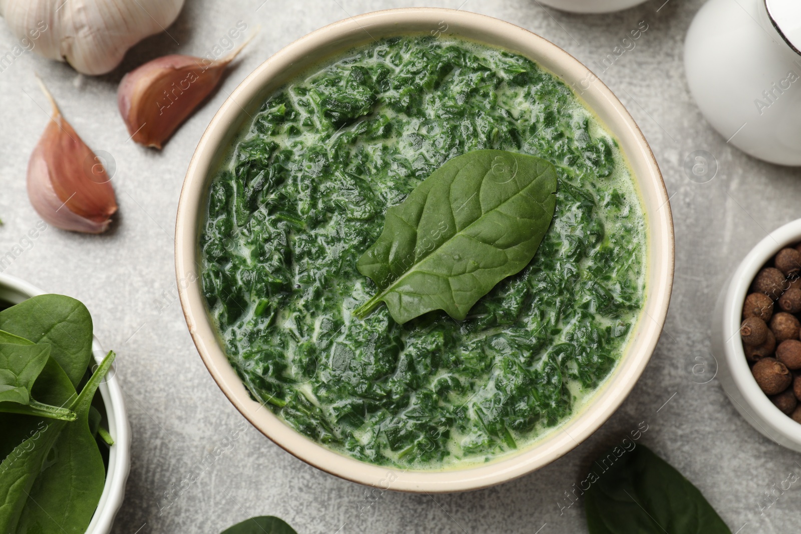 Photo of Delicious spinach sauce in bowl and spices on grey table, flat lay