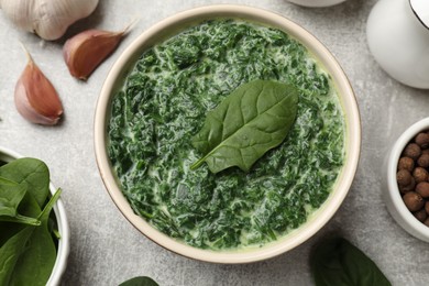 Delicious spinach sauce in bowl and spices on grey table, flat lay