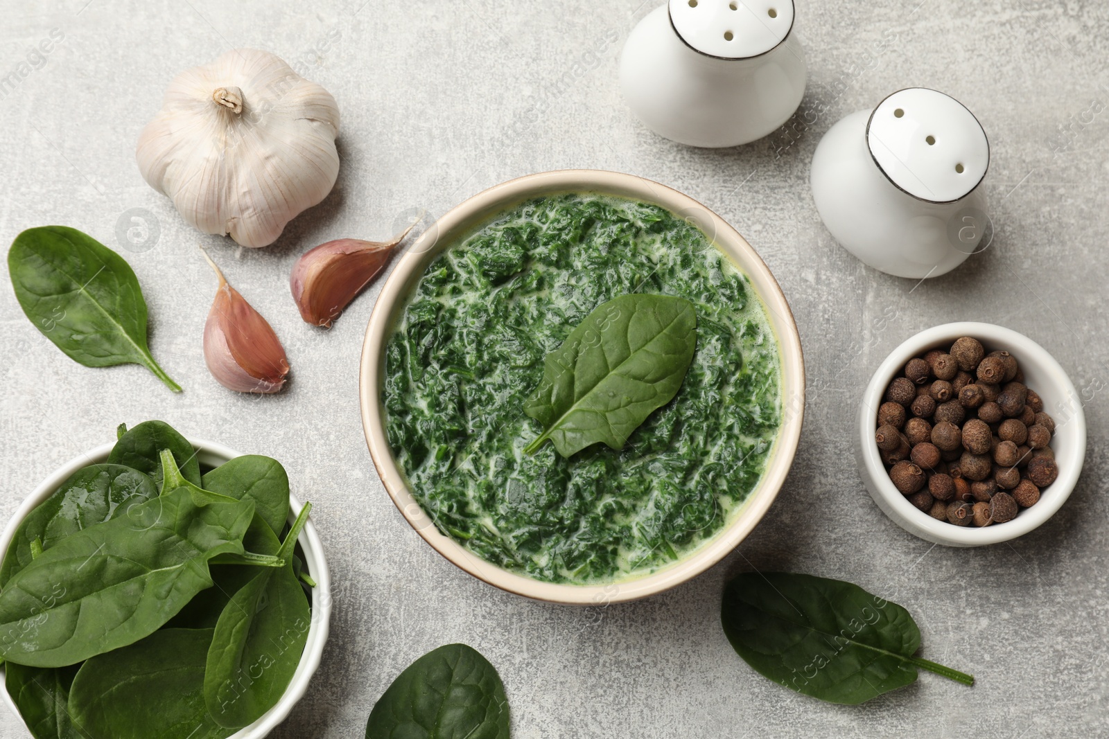 Photo of Delicious spinach sauce in bowl and spices on grey table, flat lay