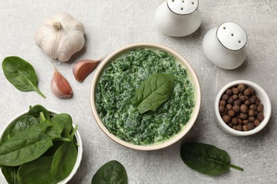 Delicious spinach sauce in bowl and spices on grey table, flat lay