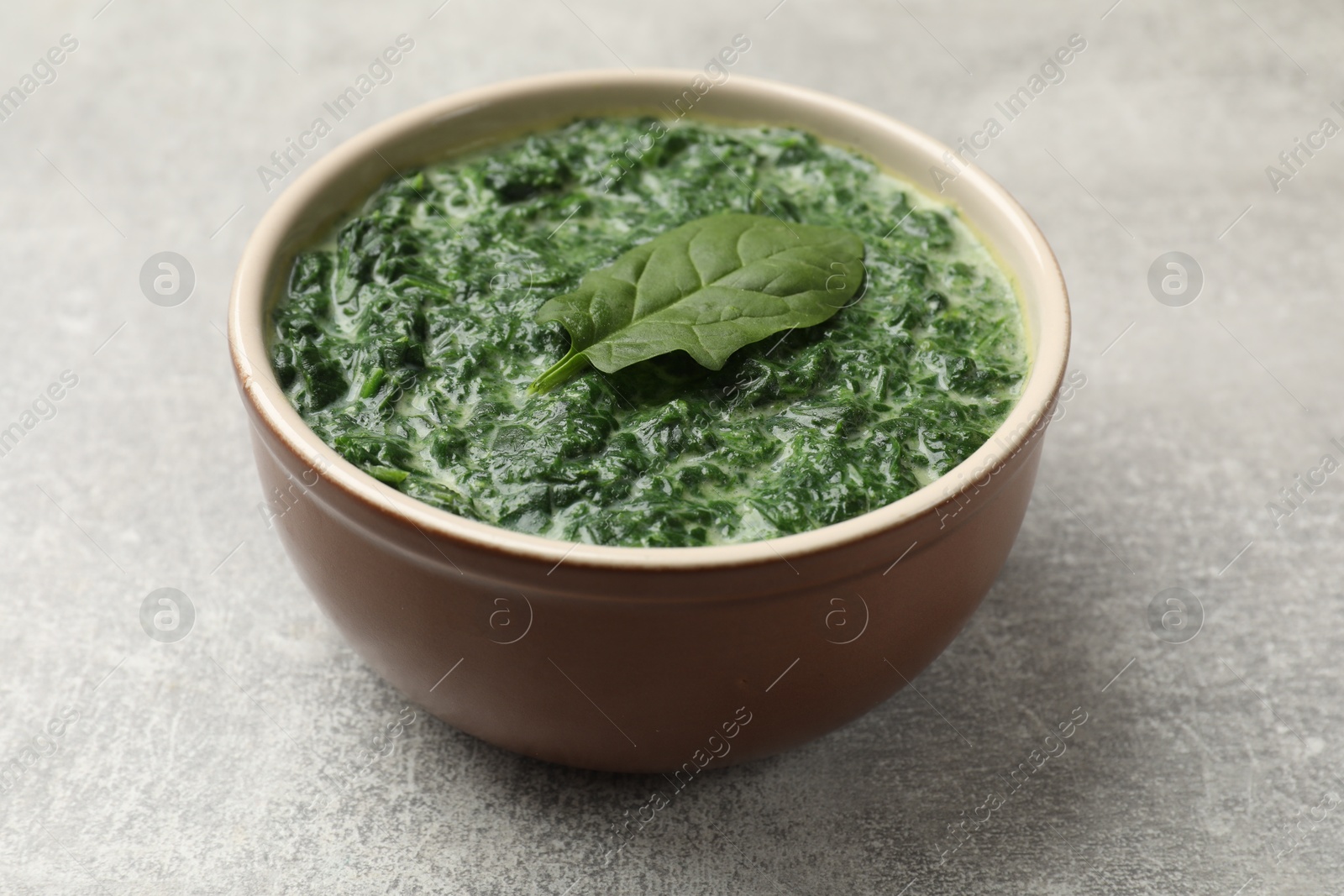 Photo of Delicious spinach sauce in bowl on grey table, closeup