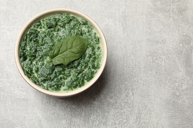 Photo of Delicious spinach sauce in bowl on grey table, top view. Space for text