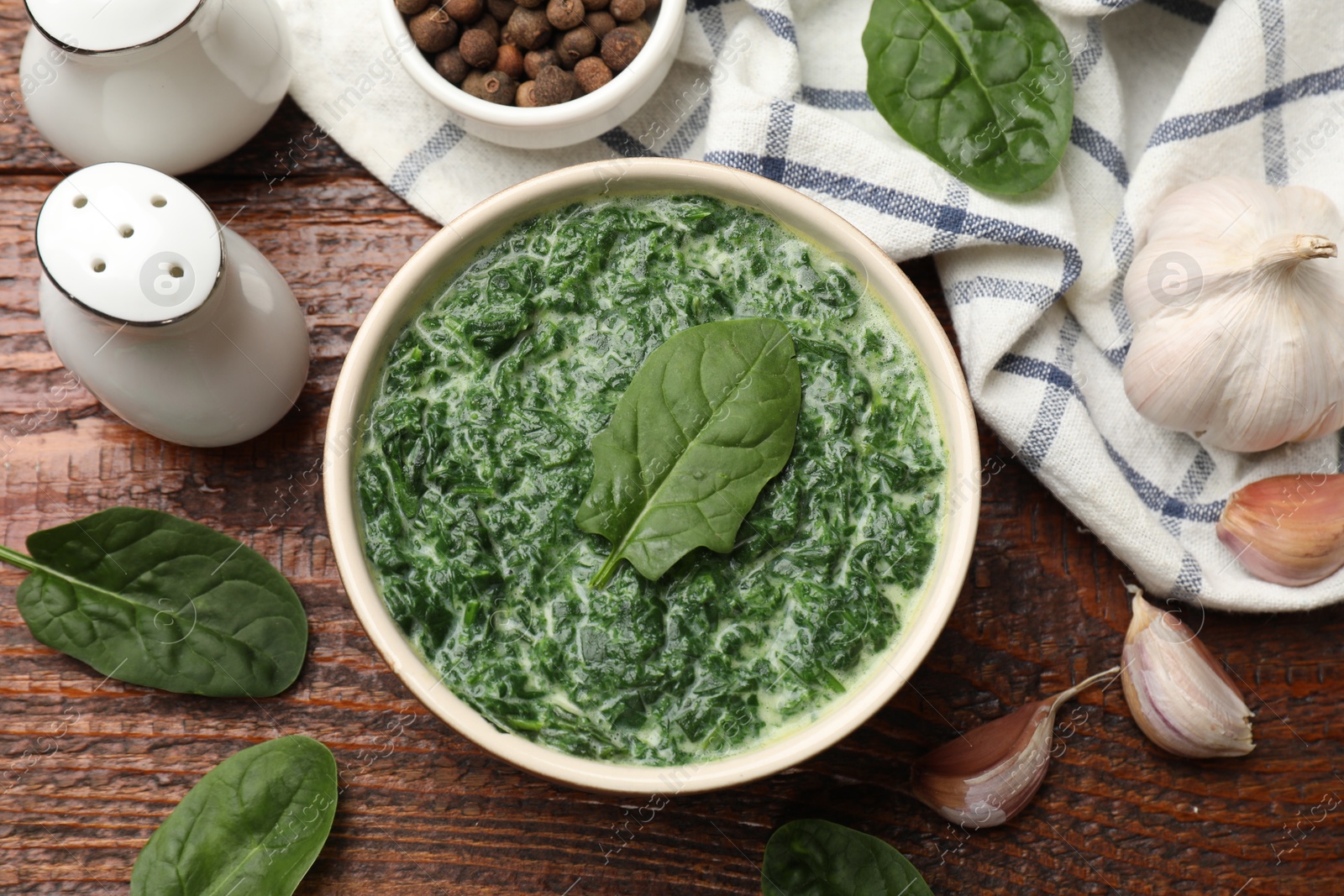 Photo of Delicious spinach sauce in bowl and spices on wooden table, flat lay