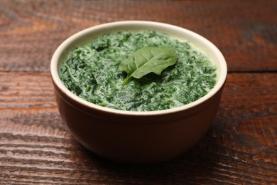 Photo of Delicious spinach sauce in bowl on wooden table, closeup