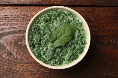 Delicious spinach sauce in bowl on wooden table, top view