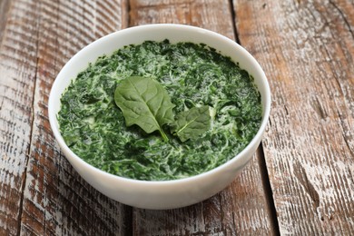 Delicious spinach sauce in bowl on wooden table, closeup