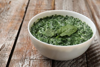 Delicious spinach sauce in bowl on wooden table, closeup. Space for text