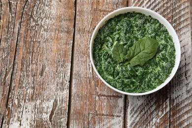 Delicious spinach sauce in bowl on wooden table, top view. Space for text