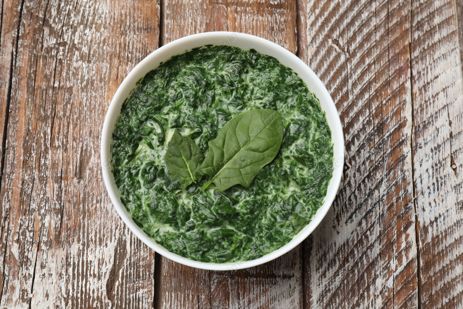 Photo of Delicious spinach sauce in bowl on wooden table, top view