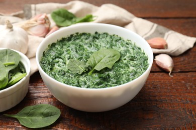 Delicious spinach sauce in bowl and spices on wooden table, closeup