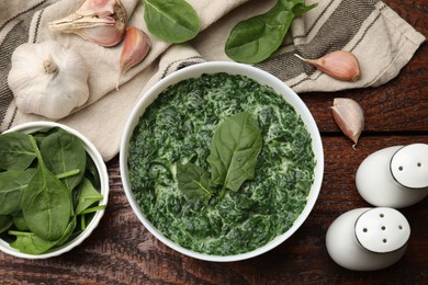 Delicious spinach sauce in bowl and spices on wooden table, flat lay