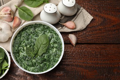 Photo of Delicious spinach sauce in bowl and spices on wooden table, flat lay. Space for text