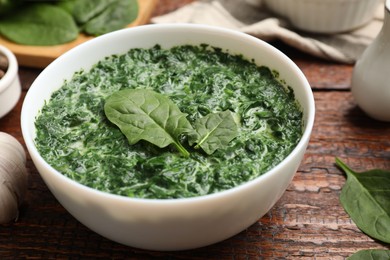 Photo of Delicious spinach sauce in bowl on wooden table, closeup