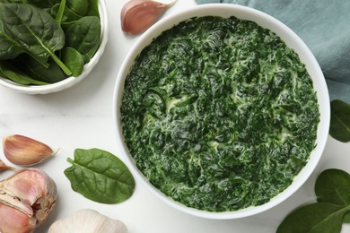 Delicious spinach sauce in bowl and spices on white marble table, flat lay