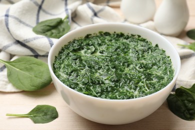 Delicious spinach sauce in bowl and leaves on wooden table, closeup