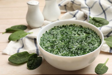 Photo of Delicious spinach sauce in bowl and leaves on wooden table, closeup