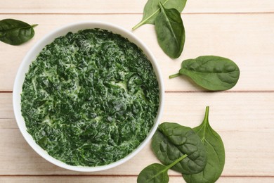 Delicious spinach sauce in bowl and leaves on wooden table, flat lay