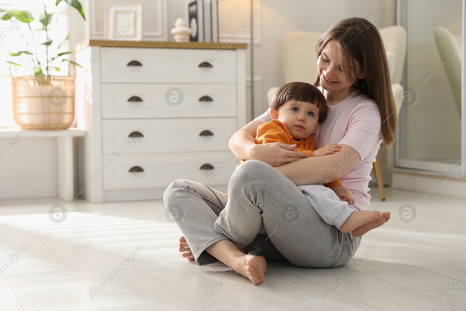 Photo of Happy mother hugging her little son at home. Space for text