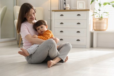 Photo of Happy mother hugging her little son at home. Space for text