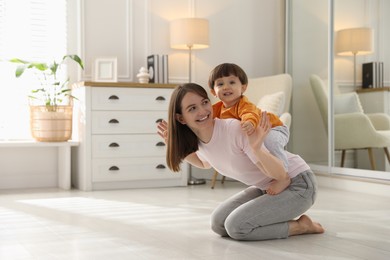 Photo of Happy mother playing with her little son at home. Space for text