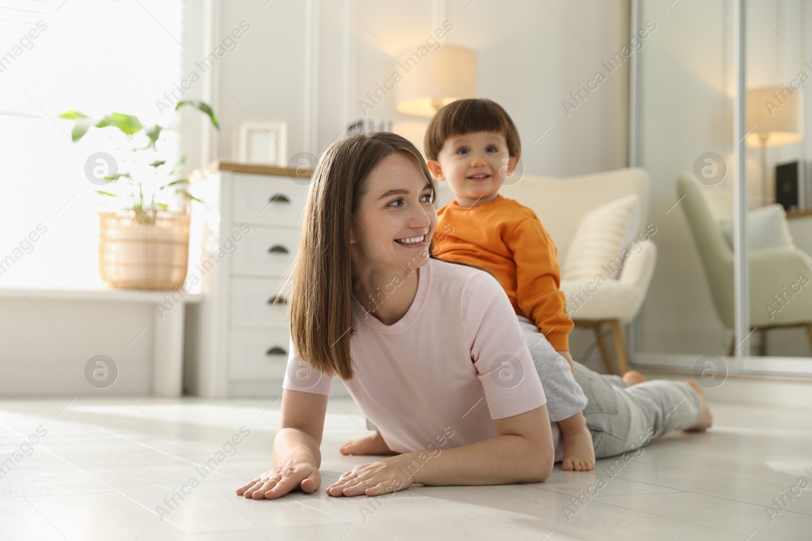 Photo of Happy mother with her little son at home. Space for text