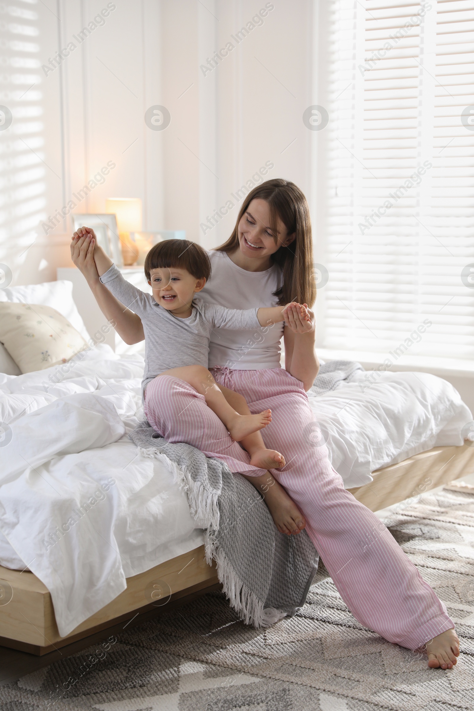 Photo of Happy mother playing with her little son in bedroom