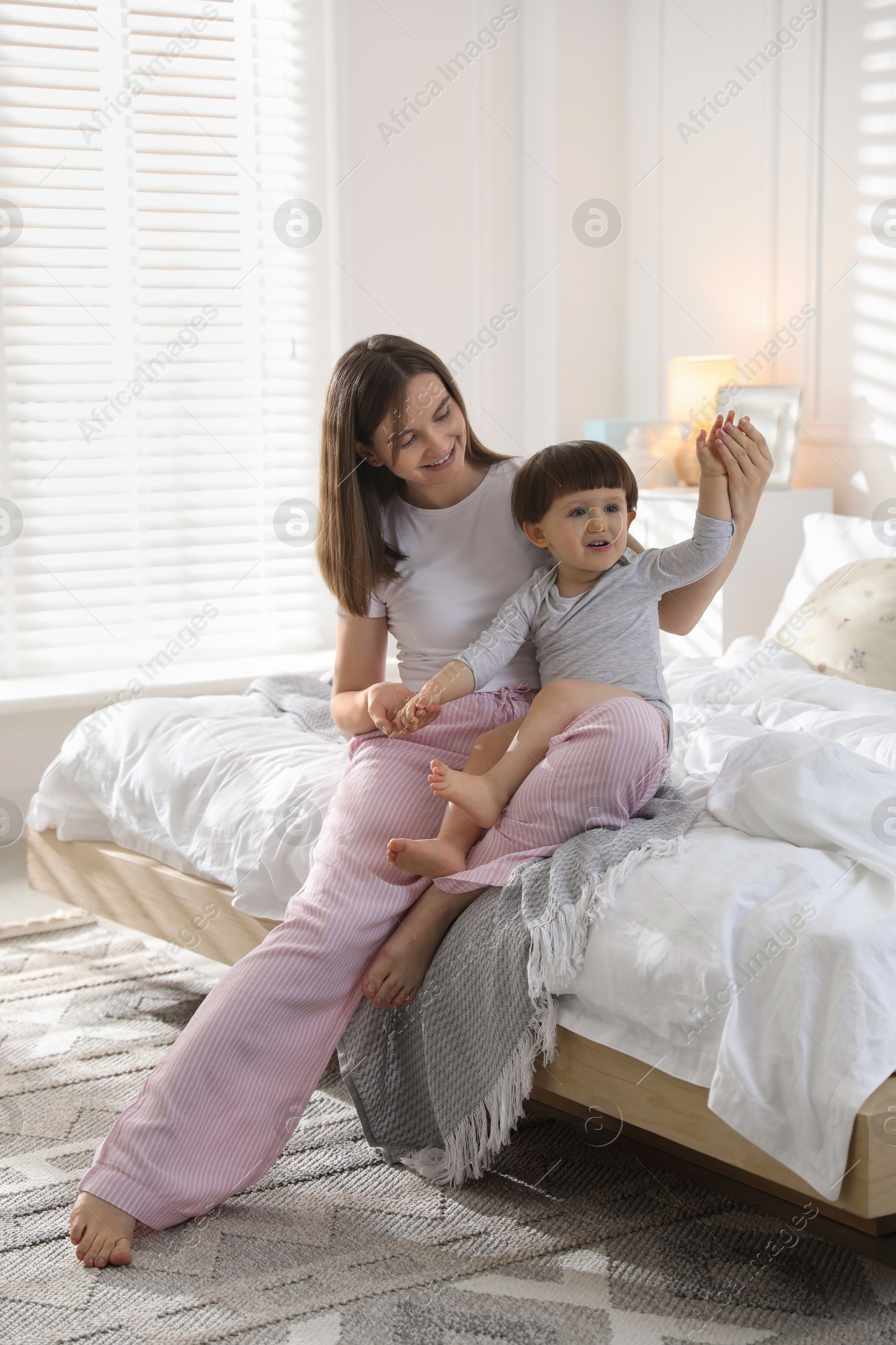 Photo of Happy mother playing with her little son in bedroom