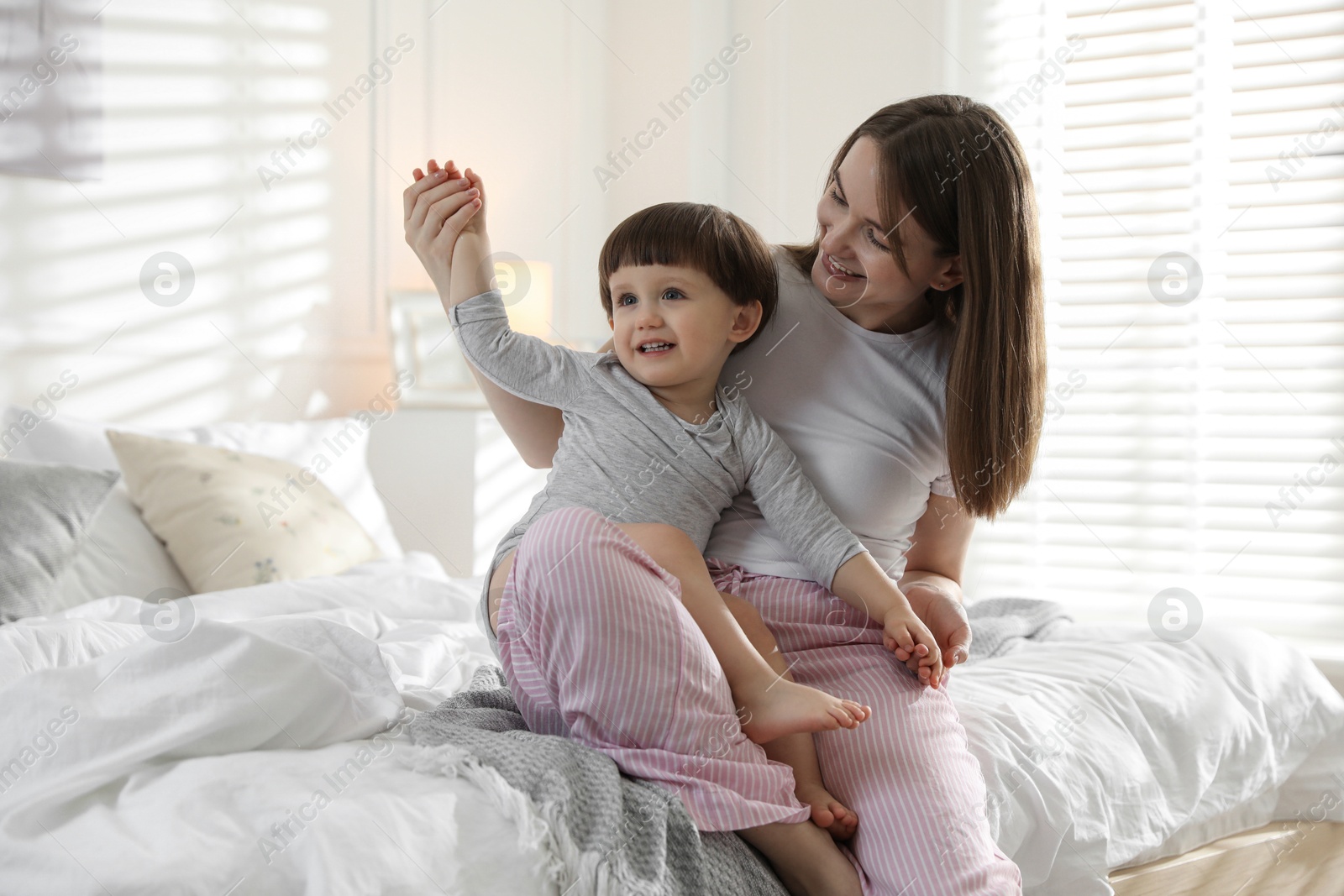 Photo of Happy mother playing with her little son in bedroom