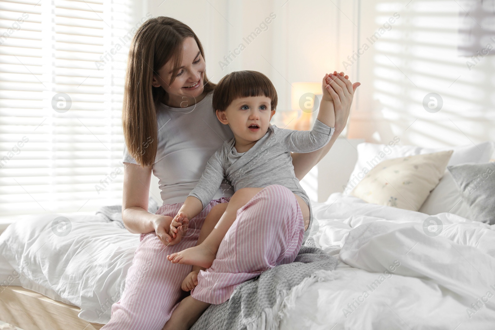 Photo of Happy mother playing with her little son in bedroom