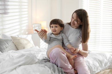 Photo of Happy mother playing with her little son in bedroom