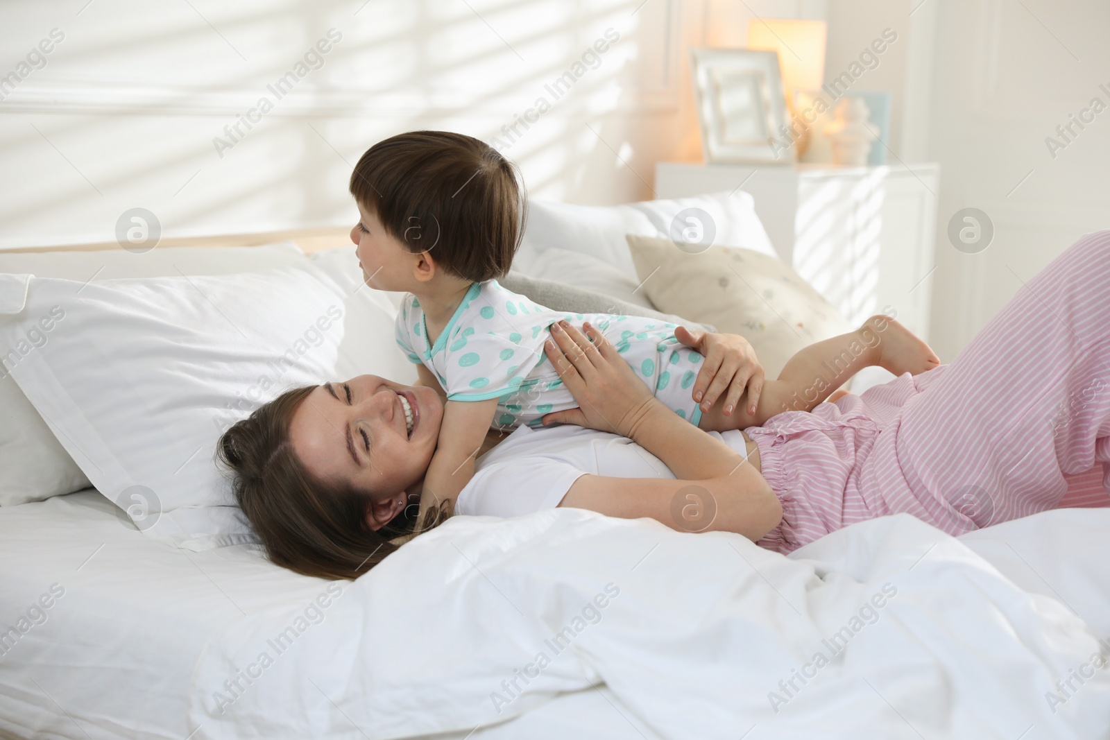 Photo of Happy mother with her little son on bed at home