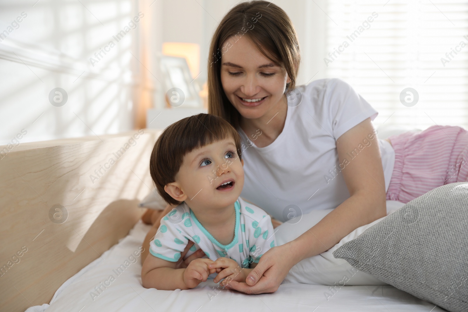 Photo of Happy mother with her little son on bed at home