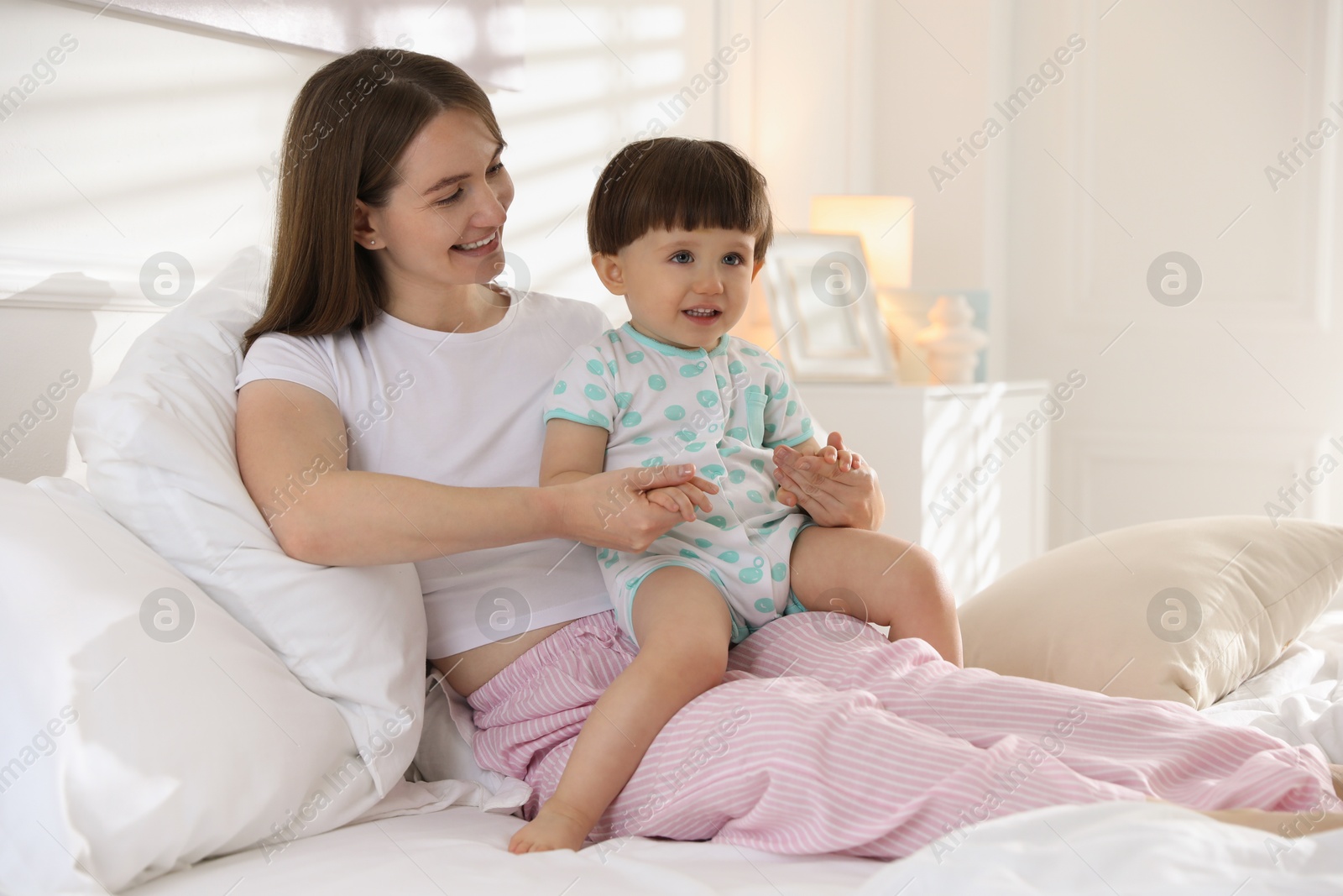 Photo of Happy mother with her little son on bed at home