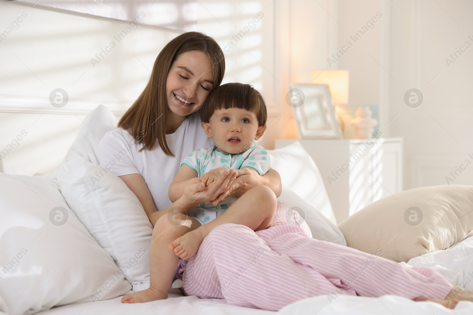 Photo of Happy mother with her little son on bed at home