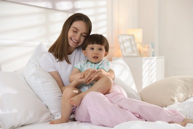 Photo of Happy mother with her little son on bed at home