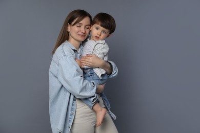 Photo of Mother hugging her little son on grey background. Space for text