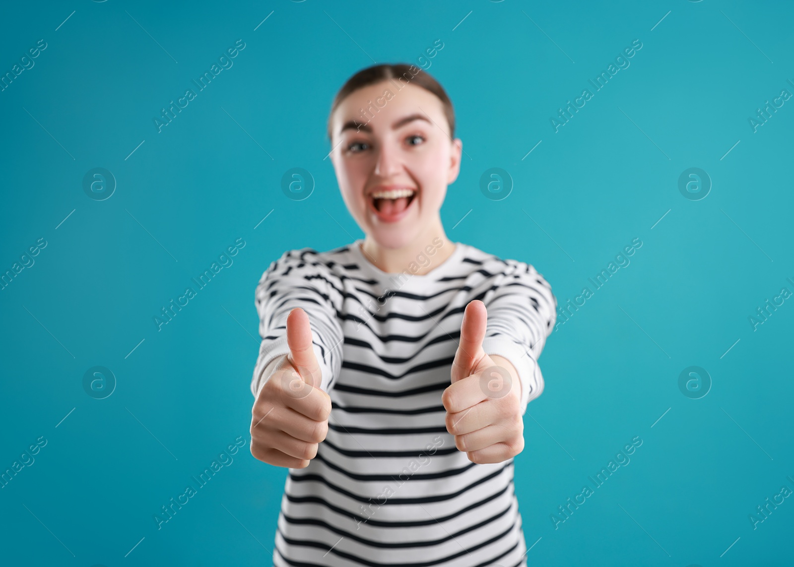 Photo of Happy woman showing thumbs up on light blue background, selective focus. Like gesture