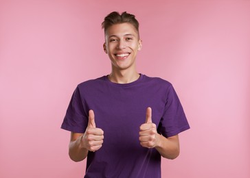 Happy man showing thumbs up on pink background. Like gesture