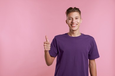 Photo of Happy man showing thumbs up on pink background, space for text. Like gesture