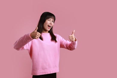 Photo of Woman showing thumbs up on pink background, space for text. Like gesture