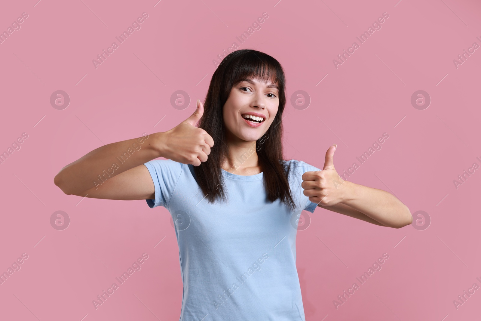 Photo of Happy woman showing thumbs up on pink background. Like gesture