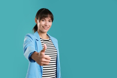 Photo of Happy woman showing thumbs up on light blue background, space for text. Like gesture