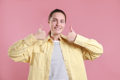 Photo of Happy woman showing thumbs up on pink background. Like gesture